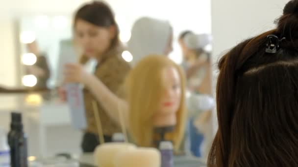 Женщина парикмахер делает объемную прическу клиенту с помощью утюга, обжига волос. Профессиональный парикмахер. Мастер делает прическу девушке в салоне красоты замедленной съемки — стоковое видео