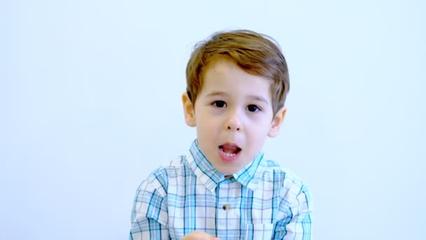 Три года ребенок и эмоции, крупным планом портрет счастливого улыбающегося ребенка, смотрящего в камеру на белом фоне — стоковое видео