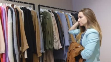Alışveriş kızı. Dükkandaki güzel bir kadının portresi. Genç esmer bir kızın portresi. Prova için bir ceket seçti. Şık giysiler içinde şık kadın