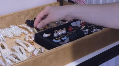 Genç bir kadın koleksiyonundan küpe seçer. moda takı, her gün için güzel aksesuarlar.