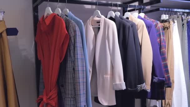 Shooting clothes woman hangers constantly in store indoors. Close up Shot clothing in score, long line with dresses, skirts, coats, sweaters, jackets, pants — Stock Video