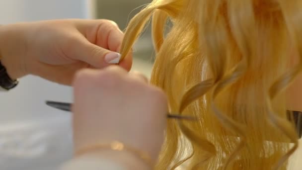 Fille étudiante coiffeur fait coiffure sur la tête factice avec de longs cheveux blonds dans le salon de coiffure léger — Video