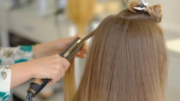 一位女理发师用熨发机给顾客做大量的发型，压头发。专业的理发师在工作。慢动作 — 图库视频影像