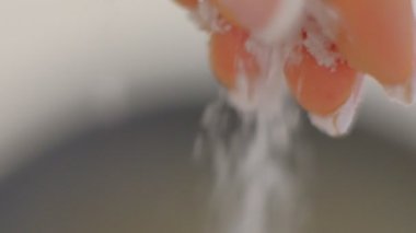 Aşçı döküm El beyaz tuz kristalleri Makro atar, Yavaş Hareket Closeup. Dişi el tuz döker.
