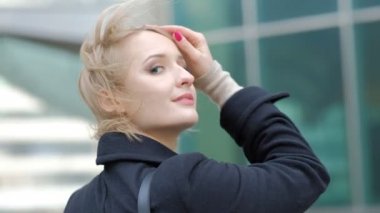 muhteşem genç kadın rüzgar ile sallayarak sarı saç kesimi doğrultuyor ve yavaş hareket bina karşı kamera için poz