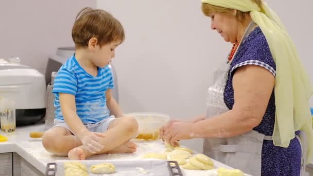 Primer plano de la feliz y sonriente abuela y nieto amasando un daugh juntos. cámara lenta de una anciana y un niño pequeño preparando pasta o pizza juntos . — Vídeos de Stock