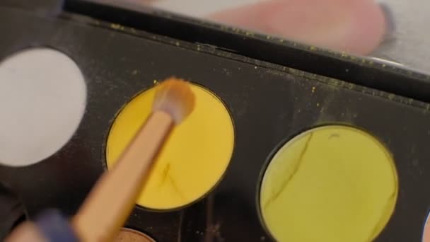 Une palette avec des ombres à paupières et un pinceau de maquillage : les cosmétiques pour femmes. Maquillage matinal. Cosmétiques décoratifs : une palette avec des ombres à paupières, un pinceau. Détails du travail des maquilleurs 