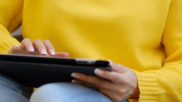 Close-up schoot jonge vrouw zitten op de Bank in huis en maakt gebruik van digitale tablet surfen op internet en het kijken naar video op tablet moderne touchpad. Slow motion — Stockvideo