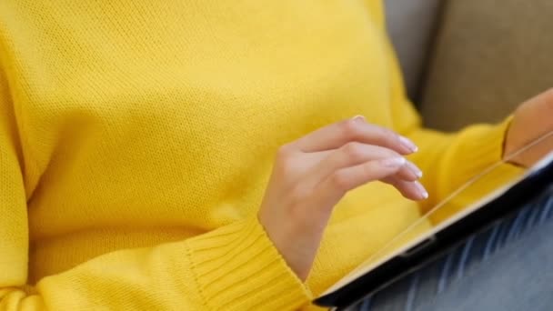 Primer plano de la Mujer Joven sentarse en el sofá en casa y utiliza la tableta digital de navegación por Internet y ver vídeo en la tableta moderna touchpad. cámara lenta — Vídeos de Stock