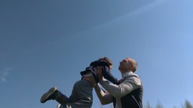Babam oğlunu yukarı yaslar, çocuk yaz güneşli bir gün. Yavaş Çekim. baba ve oğlu açık havada eğlenmek