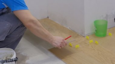 Bir adam yere çimento üstüne bir kiremit yerleştirir. Kiremit bir kesme meşe boyama vardır