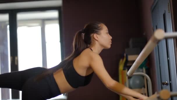 Fille aux cheveux foncés danseuse professionnelle en haut et collants montre des mouvements de bras de ballet tenant la main courante au ralenti — Video