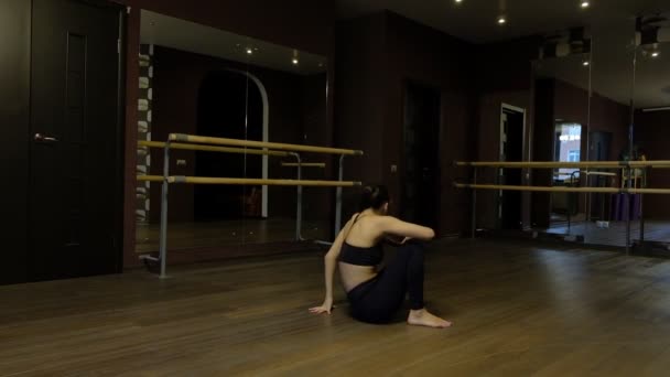 Girl dancer with ponytail in black tights demonstrates body flexibility doing exercise coup back on floor slow motion — Stock Video