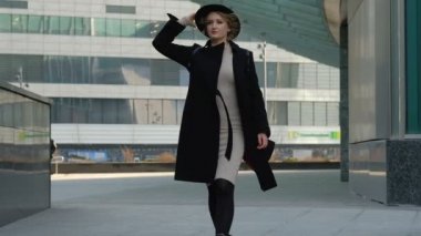 sırt çantası ile sarışın kız sokakta şapka koyarak yürüyor