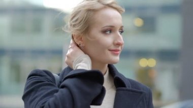 muhteşem genç kadın rüzgar ile sallayarak sarı saç kesimi doğrultuyor ve yavaş hareket bina karşı kamera için poz