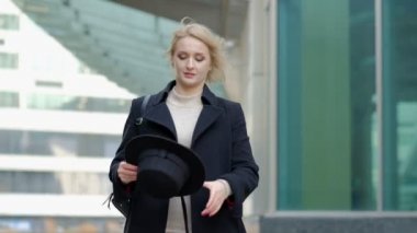 Kadın modern siyah şapkayla oynuyor geniş kenarlı chapeau siyah ceketin altında yavaş çekimde düşük açılı çekimde