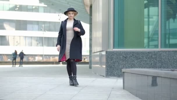 Mujer juega con sombrero negro moderno movimiento de ala ancha chapeau en la parte inferior del abrigo negro en la calle de cámara lenta de ángulo bajo disparo — Vídeos de Stock