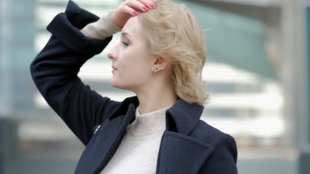 Menina endireita o corte de cabelo loiro acenando pelo vento e poses — Vídeo de Stock