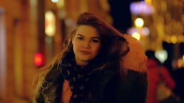 Uzun saçlı sokak boyunca yürüyüş, kırmızı ışıklar altında geceleri kulaklık giyen müzik dinleme ile closeup genç kız. Yavaş hareket.