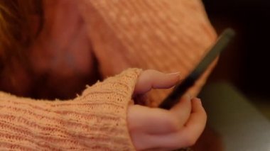 Ödev yaparken akıllı telefon kullanan genç bir kadın. Hispanik insanlar ve üniversite eğitimi. Çalışan ve cep telefonuyla mesajlaşan kız öğrenci