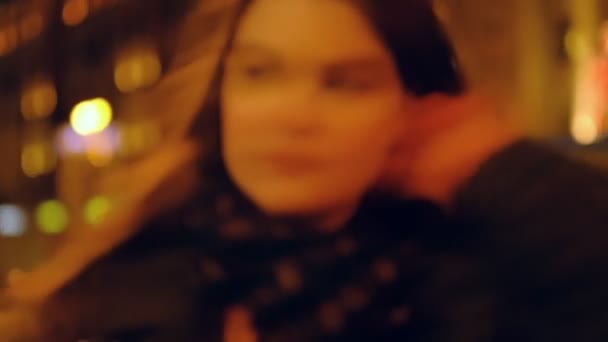 Closeup tizenéves lány, hosszú hajú séta az utcán, és hallgatta a zenét visel fejhallgatót éjjel a piros lámpák. Lassú mozgás. — Stock videók