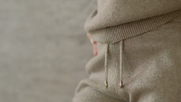Flicka i en grå sticka Sweatshirt står mot en vägg, hennes händer i hennes fickor. — Stockvideo