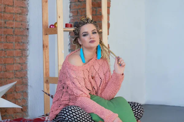 Beautiful plus size girl lying on the sofa. n a warm pink sweater and bright earrings. boho style — Stock Photo, Image