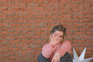 Kanepede yatan güzel artı boyutu kız. n sıcak pembe kazak ve parlak küpe. Boho tarzı