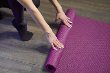 Genç yoga Kadın bir pencere yakınında ahşap zemin üzerinde bir yoga dersi sonra onu leylak mat haddeleme, yakın