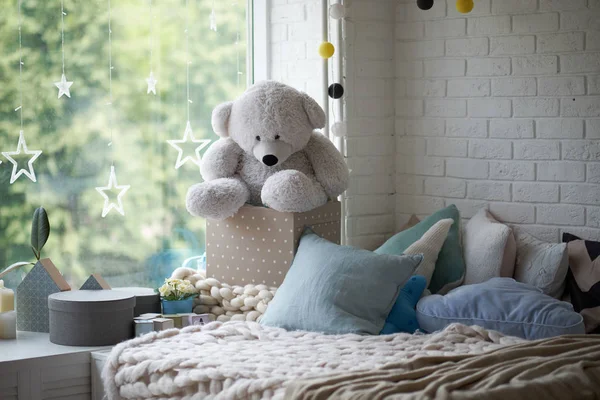 Gezellige kinderkamer in heldere zachte kleuren, kussens en een deken liggen op het bed — Stockfoto