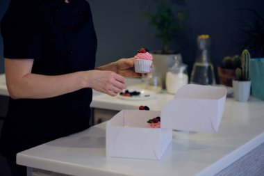 kadın aşçı cupcakes bir kutu içinde ambalaj olduğunu. küçük işletme kavramı. genç kadın iş kadını ofisinde çalışıyor.