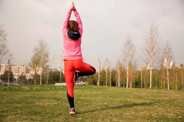 Young woman exercise yoga in the city hands up and balancing standing on one leg in sunny day. — Stock Photo, Image