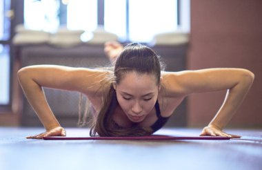 Güzel Asyalı kadın bazı ağırlık kaldırmadan önce spor salonunda push up yapıyor