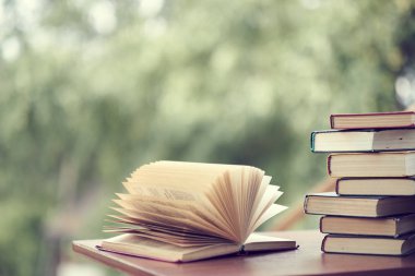 kitap yığını masanın üzerinde yatıyor. ev kütüphanesi. doğada gadget'lar tatil kavramı