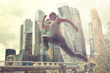 Fit vücut atlama ve çalışan genç kadın. Spor giyimde kadın model açık havada egzersiz yapıyor.