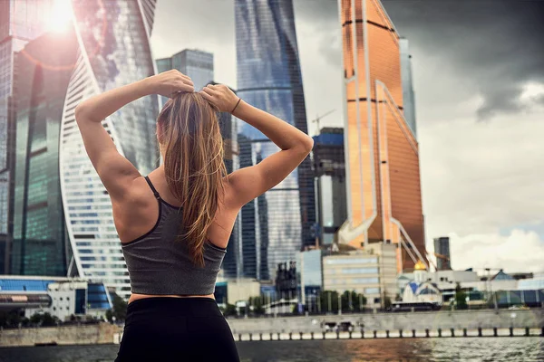 pembe takım elbiseli genç kadın yaz sabahı erken saatlerde spor eğitimiiçin hazırlanıyor. saç için bir lastik bant ile kuyruk saç toplar.