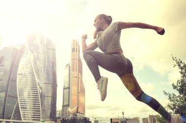 Fit vücut atlama ve çalışan genç kadın. Spor giyimde kadın model açık havada egzersiz yapıyor.