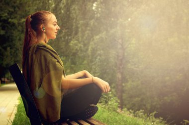 Park'ta yoga yapan beyaz bir kadın. Lotus pozisyonunda oturmak.