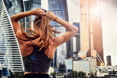 pembe takım elbiseli genç kadın yaz sabahı erken saatlerde spor eğitimiiçin hazırlanıyor. saç için bir lastik bant ile kuyruk saç toplar.