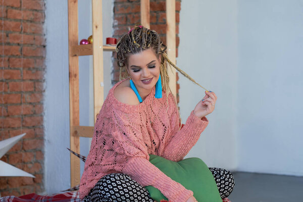 Мбаппе плюс размер девочки, лежащей на диване. в теплом розовом свитере и ярких сережках. Стиль Фабрегаса
