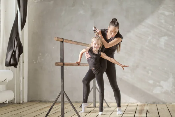 Sierlijk meisje ballerina staande op handen en stretching met leraar in dansstudio — Stockfoto