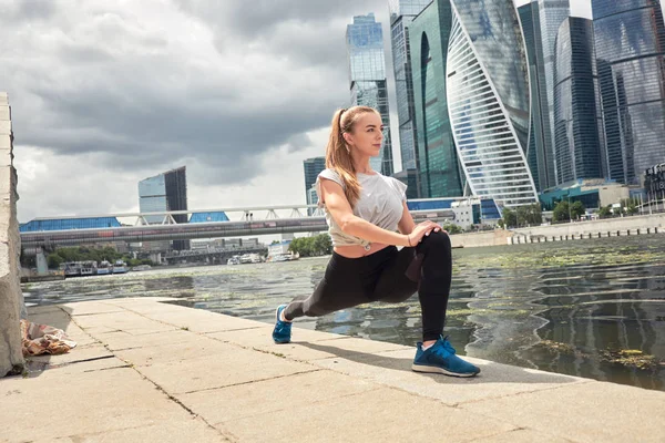 genç kadın büyük bir şehrin sokakta bir egzersiz yapar. güzel atletik kız