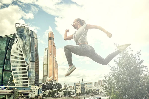 Fit vücut atlama ve çalışan genç kadın. Spor giyimde kadın model açık havada egzersiz yapıyor.