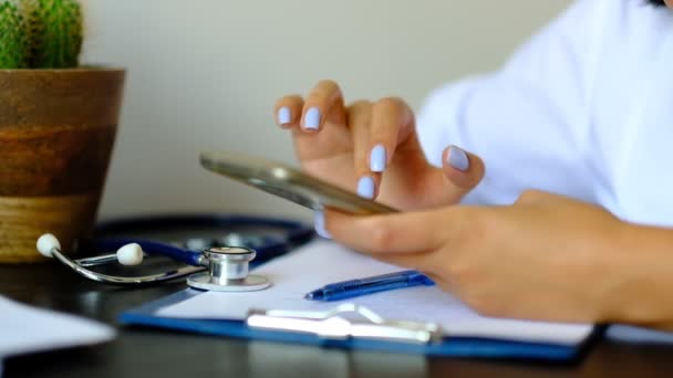 En cámara lenta. Primer plano Manos de médico profesional desplazándose en el teléfono inteligente, consultando al paciente en línea — Vídeo de stock