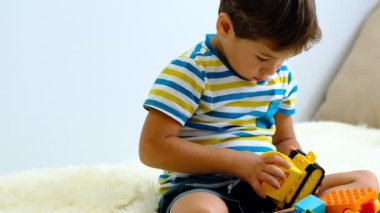 evde beyaz Yatak üzerinde renkli inşaat plastik bloklar ile oynarken yavaş hareket asya çocuk .