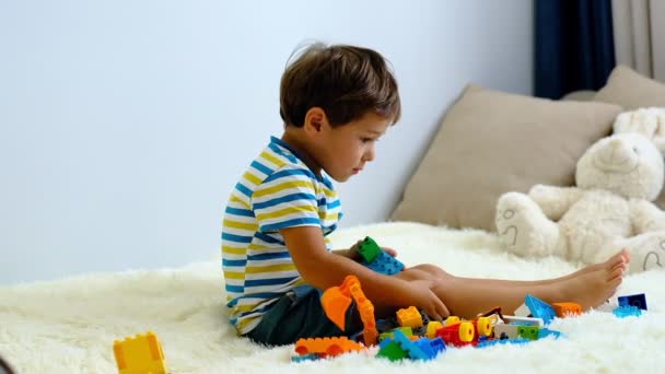 Lassú mozgás ázsiai fiú játszik a színes építési műanyag blokkok fehér ágy otthon . — Stock videók