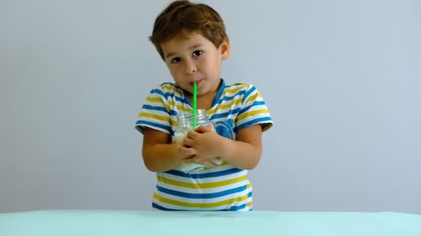 Slow motion asiático bonito menino bebendo leite na cozinha. menino alegre gosta de beber milkshake — Vídeo de Stock