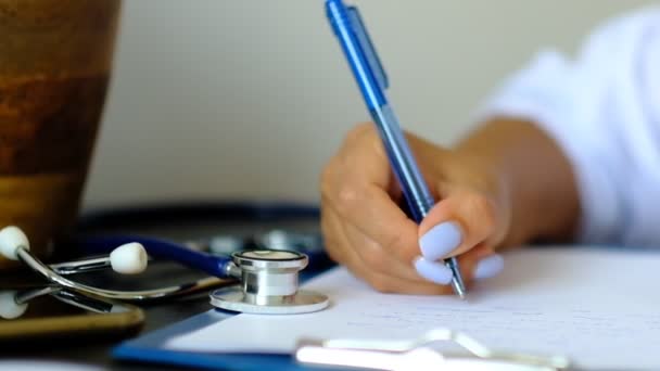 Joven terapeuta llenando la lista médica sentada en el escritorio. Concepto de salud y seguro. Doctora haciendo papeleo en el consultorio . — Vídeo de stock