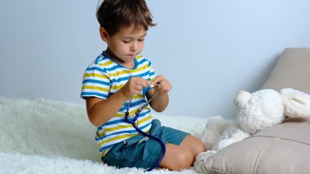 Замедление. Маленький мальчик играет в доктора, ребенок лечит своего игрушечного кролика. Доктор и пациент. Концепция медицины и здравоохранения — стоковое видео