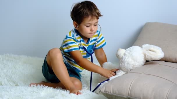 慢动作。小男孩扮演医生，孩子治疗他的玩具兔子。医生和病人医学与保健概念 — 图库视频影像